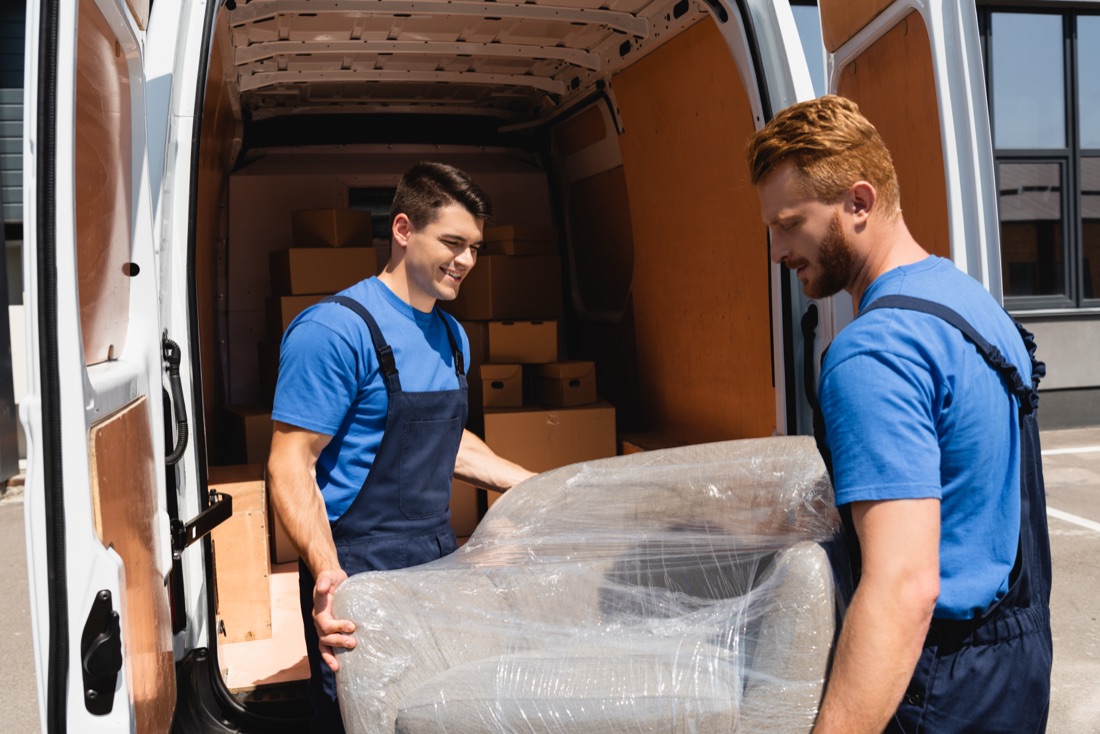 A mover carefully loading an armchair into the moving truck